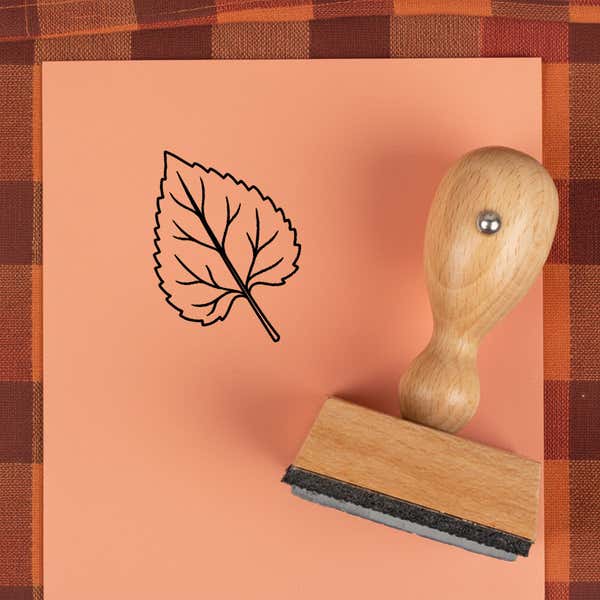 Toothed teardrop leaf stamped in black on peach cardstock on a plaid autumn cloth