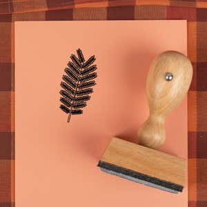 Fern frond stamped in black on peach cardstock on a plaid autumn cloth