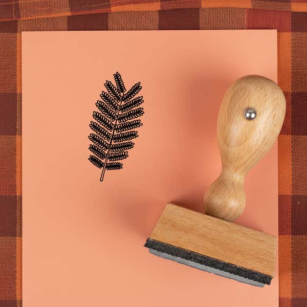 Fern frond stamped in black on peach cardstock on a plaid autumn cloth