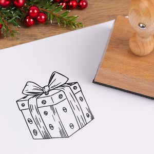 Wrapped gift box stamped in black on white cardstock styled with red berries and pine greenery