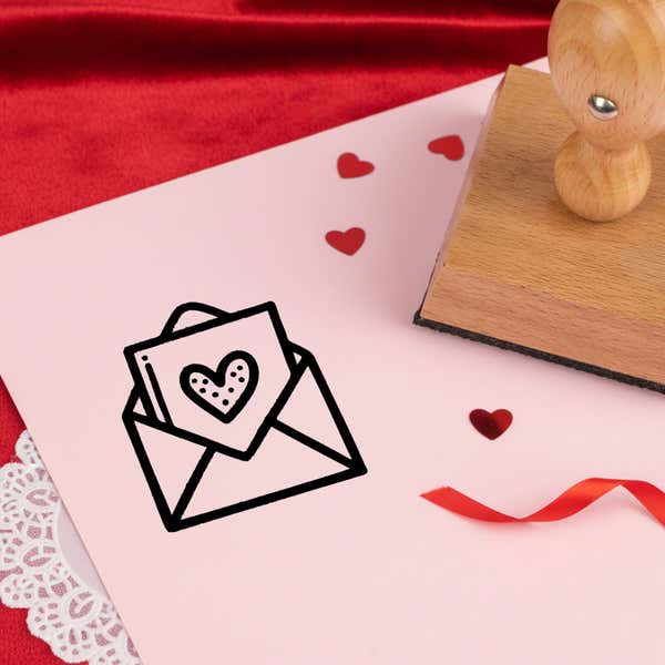 heartfelt love letter stamped in black on pink cardstock with red heart confetti, ribbon, a lace doily and the stamp