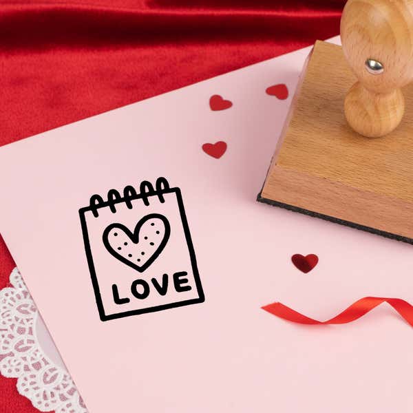 sweet love notepad stamped in black on pink cardstock with red heart confetti, ribbon, a lace doily and the stamp