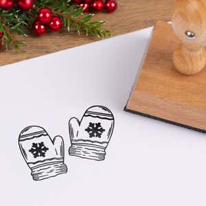 Cozy mittens stamped in black on white cardstock styled with red berries and pine greenery