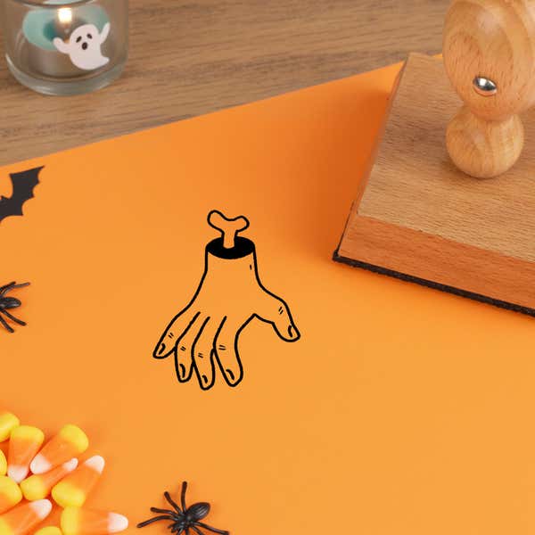 gruesome severed hand stamped in black on orange cardstock beside candy corn, a plastic spider and a ghost tea light