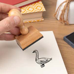 Hand pressing the Sketched Goose Craft Stamp onto cardstock beside a black ink pad