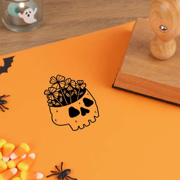 gothic skull plant stamped in black on orange cardstock with candy corn and plastic spiders at the corners