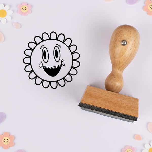 Grinning retro flower stamped in black on lavender cardstock with smiling daisy confetti