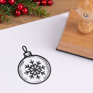 Winter snowflake ornament stamped in black on white cardstock styled with red berries and pine greenery