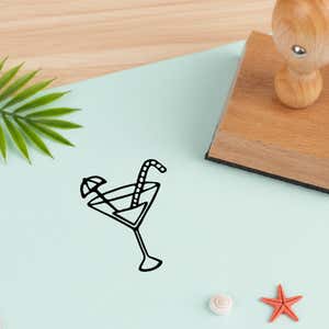 tropical drink stamped in black on pale aqua cardstock beside a palm frond, a white seashell and a coral starfish