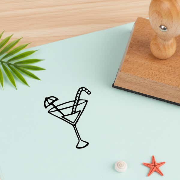 tropical drink stamped in black on pale aqua cardstock beside a palm frond, a white seashell and a coral starfish