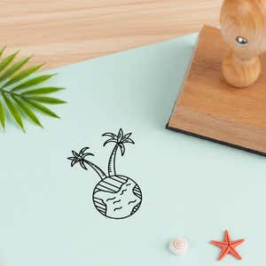 tropical globe stamped in black on pale aqua cardstock beside a palm frond, a white seashell and a coral starfish