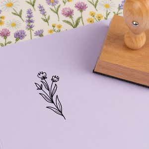 Dainty bud stems stamped in black on lilac cardstock on wildflower-print fabric