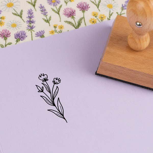 Dainty bud stems stamped in black on lilac cardstock on wildflower-print fabric