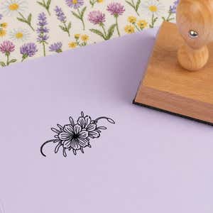 Wide floral spray stamped in black on lilac cardstock on wildflower-print fabric
