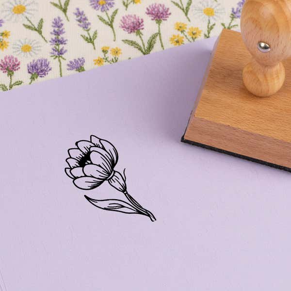 Layered petal bloom stamped in black on lilac cardstock on wildflower-print fabric