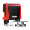 Red Trodat 4911 self-inking clothing stamp angled beside a boxed name imprint in the Bold font, a heavy condensed all-caps print.