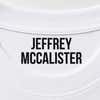 Close-up of a name stamped inside a white t-shirt collar in the Bold font, a heavy condensed all-caps print.