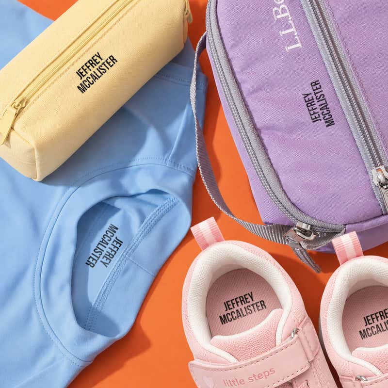 Kids' pencil case, shirt, lunch bag and sneakers name-stamped in the Bold font, a heavy condensed all-caps print, with a SimplyStamps clothing stamp.