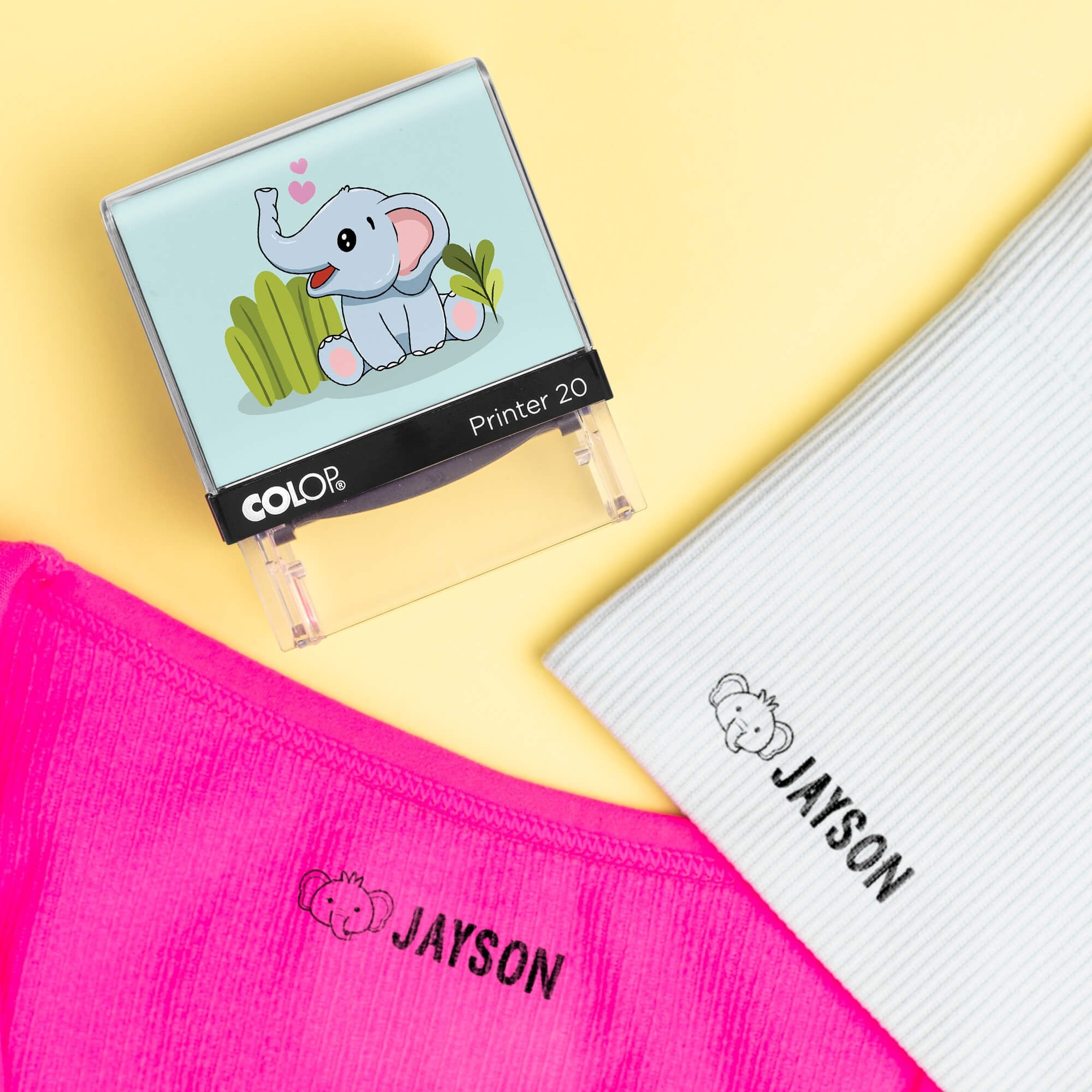 Elephant clothing name stamp beside pink and light gray shirts labeled Jayson