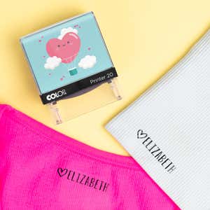 Heart clothing name stamp beside pink and gray shirts labeled Elizabeth