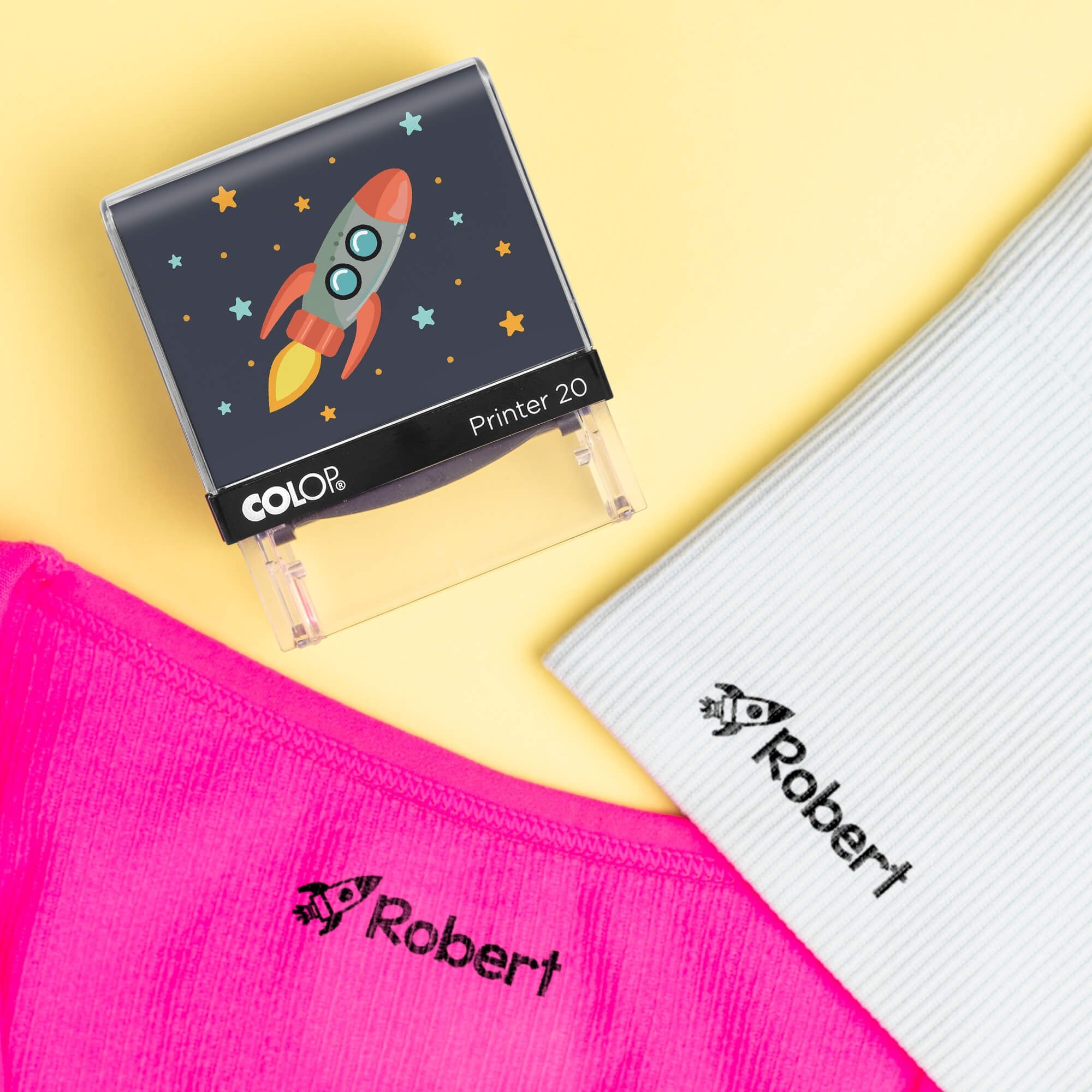 Rocket clothing name stamp beside pink and light blue shirts labeled Robert