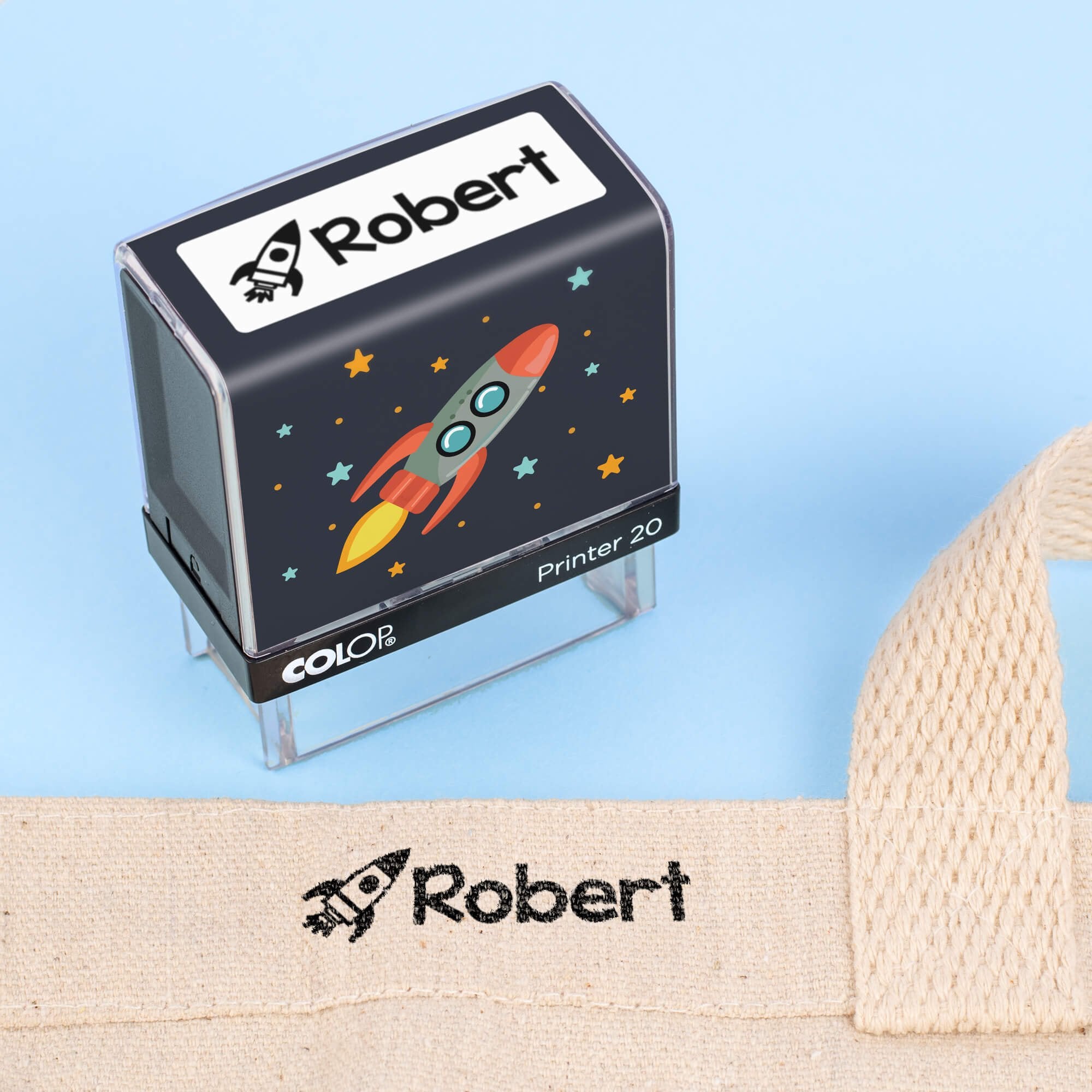 Rocket clothing name stamp beside a canvas tote bag labeled Robert