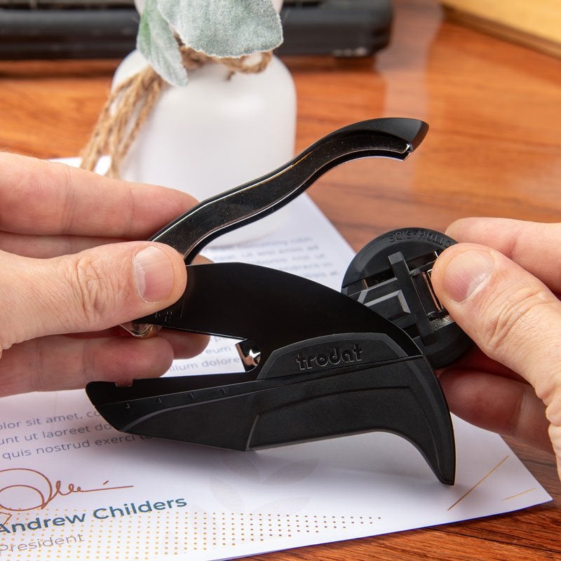 Hands inserting custom plate into an embosser for storing
