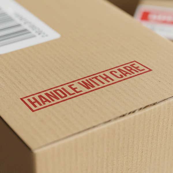 Wooden rubber stamp making handle with care impression on shipping box