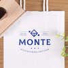 Business logo stamp printed on a white shopping bag using a wood handle rubber stamp.