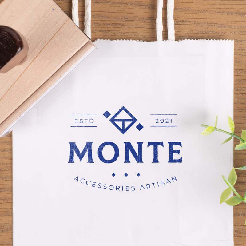 Business logo stamp printed on a white shopping bag using a wood handle rubber stamp.