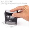 Close-up image of hand pressing a self-inking stamp showing 1 inch by 2.5 inch impression area for clear stamping results.