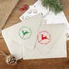 Green and red ink impressions of ‘Leaping Reindeer Holiday’ return address stamp on Christmas envelopes.