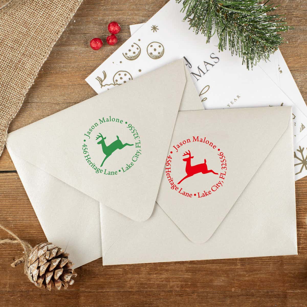 Green and red ink impressions of ‘Leaping Reindeer Holiday’ return address stamp on Christmas envelopes.