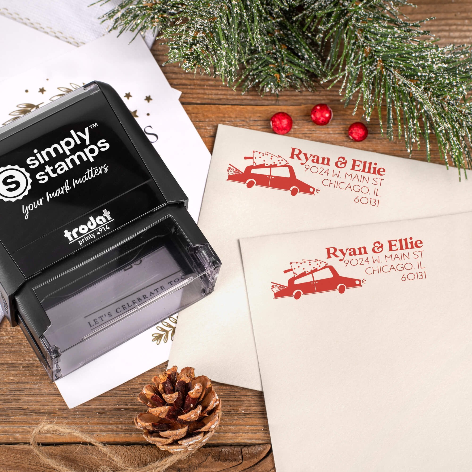 Holiday-themed ‘Christmas Car’ address stamp, hand using self-inking Christmas tree address stamp to personalize a holiday envelope on festive wooden table.