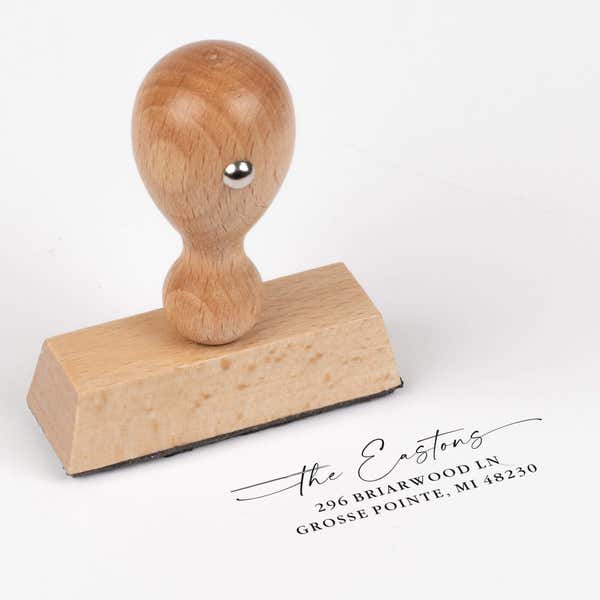 European wood hand stamp shown from above featuring custom ‘Signature Script Family Name’ holiday return address design.