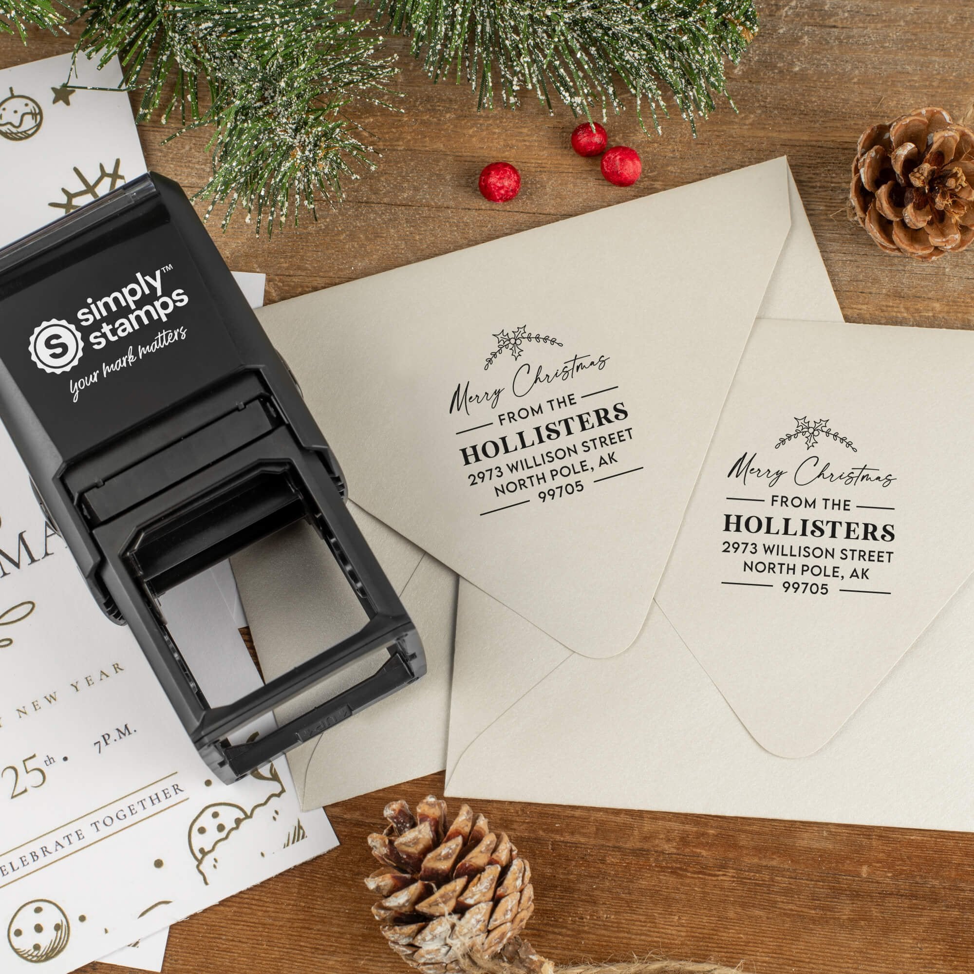 Holiday-themed ‘Merry Christmas’ address stamp shown on envelopes beside festive stationery, pinecones, and decorations.