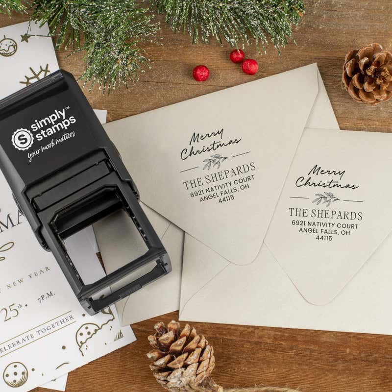 Holiday-themed ‘Magnolia Merry Christmas’ address stamp shown on envelopes beside festive stationery, pinecones, and decorations.