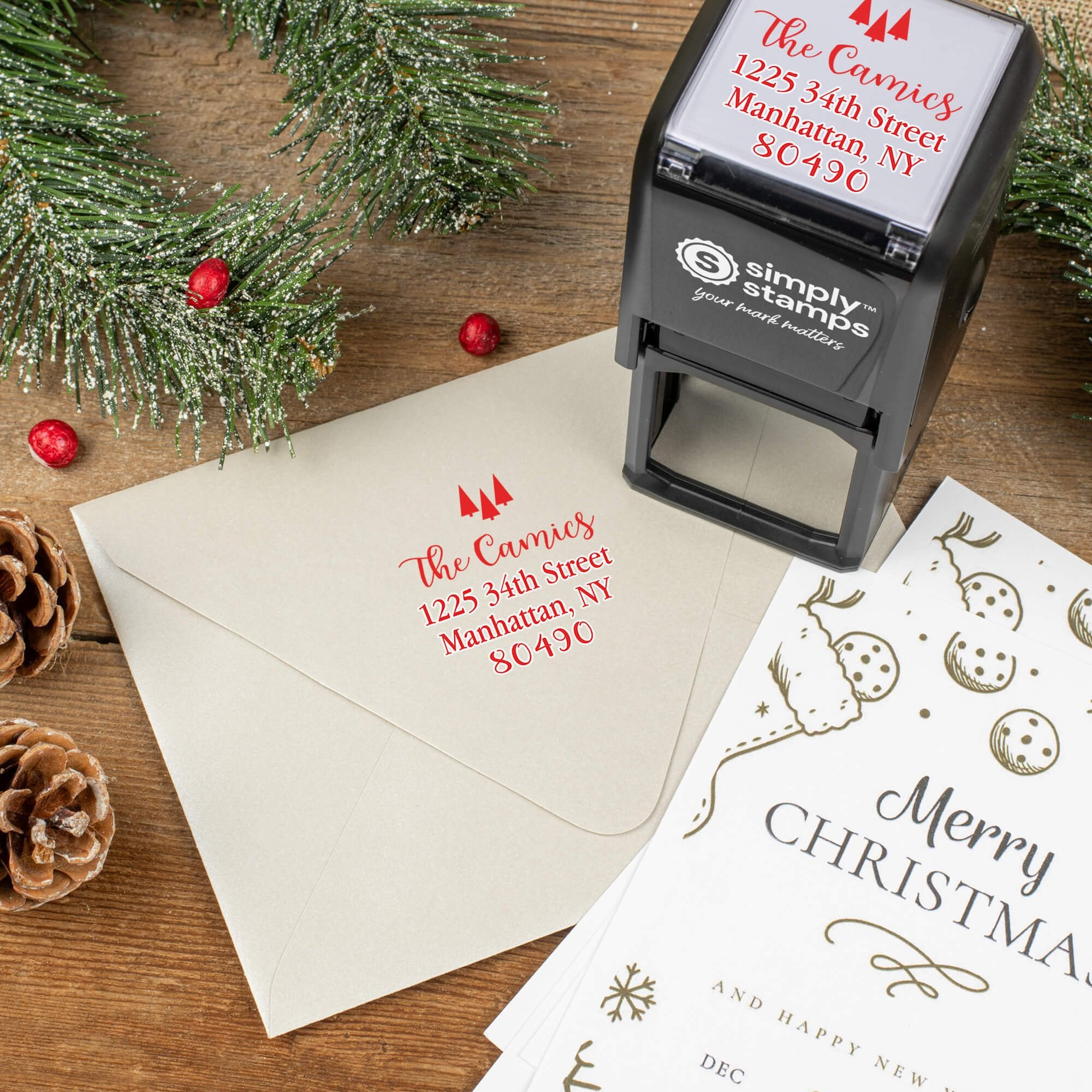 Holiday-themed ‘Tiny Trees Christmas’ address stamp shown on envelopes beside festive stationery, pinecones, and decorations.
