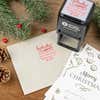 Holiday-themed ‘HoHoHo Christmas’ address stamp shown on envelopes beside festive stationery, pinecones, and decorations.