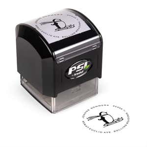Pre-inked stamp shown from above featuring custom ‘Sledding Penguin Holiday’  holiday return address design.