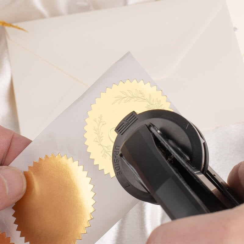 Applying embossed detail to metallic stickers using custom handheld embosser and gold foil seals