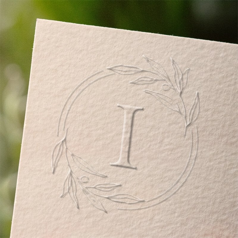 Botanical Wreath Initial Wedding Embosser with single initial impression on a sheet of paper