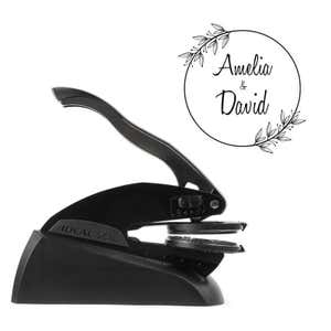 Side view of Ideal Seal custom embosser with sample wedding design shown beside it