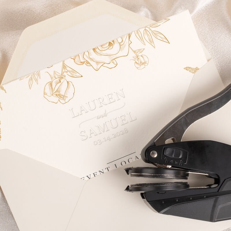 Custom embosser resting on an invitation with an example of the embossed design visible