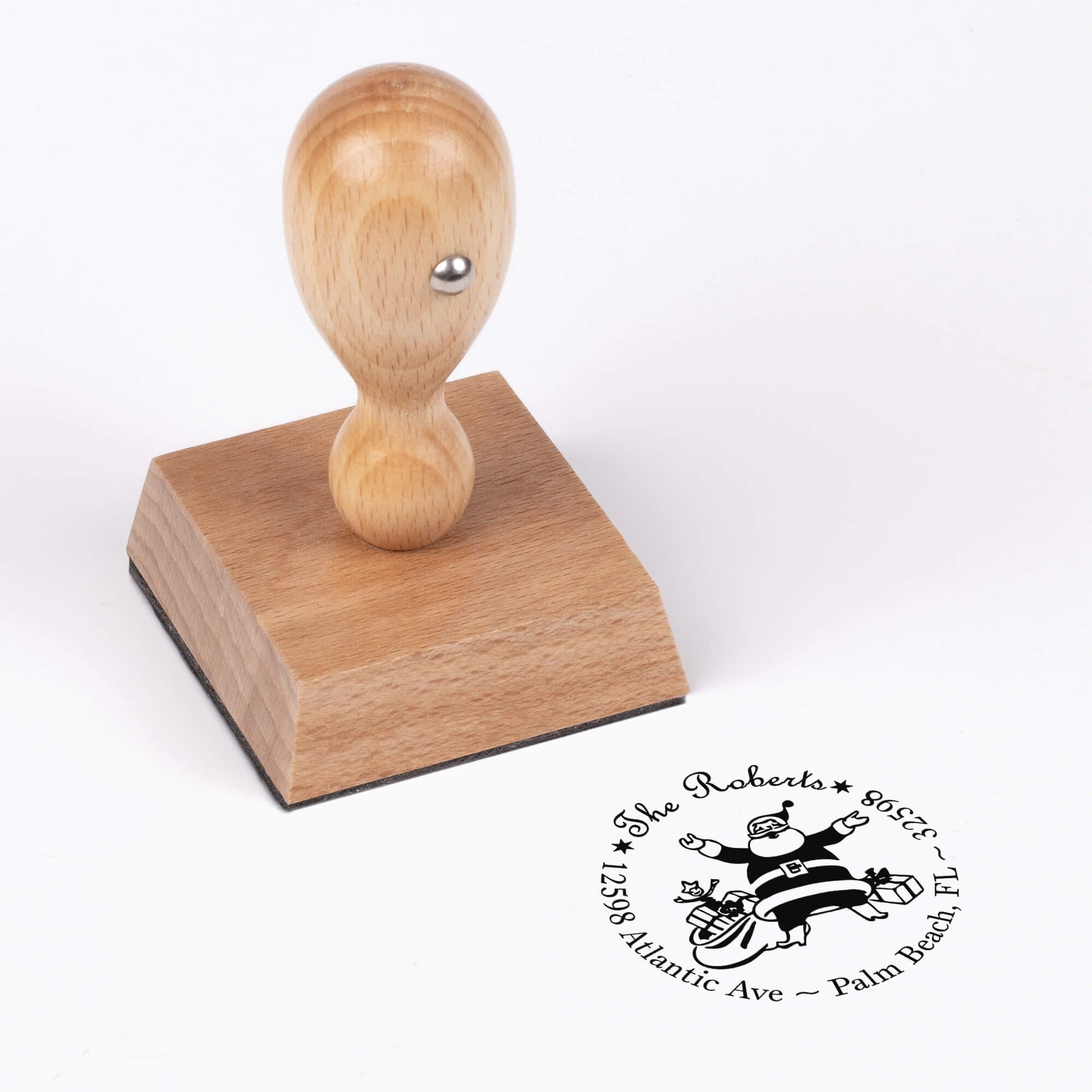 European wood hand stamp shown from above featuring custom ‘Roberts Santa Round’ holiday return address design.