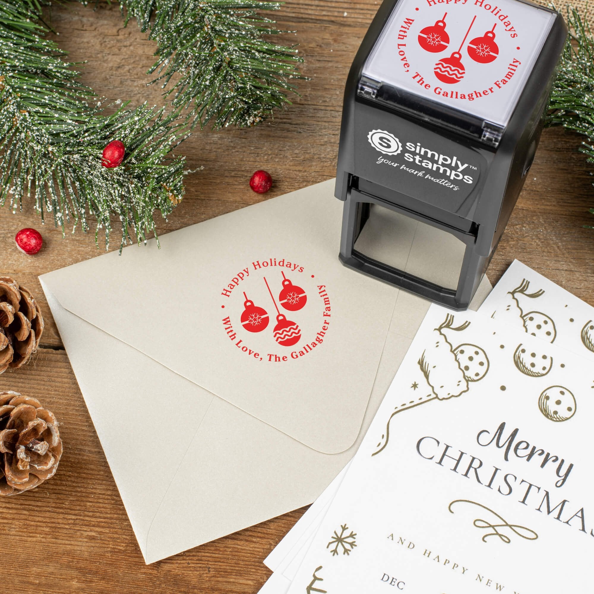Holiday-themed ‘Three Christmas Ornaments’ address stamp shown on envelopes beside festive stationery, pinecones, and decorations.