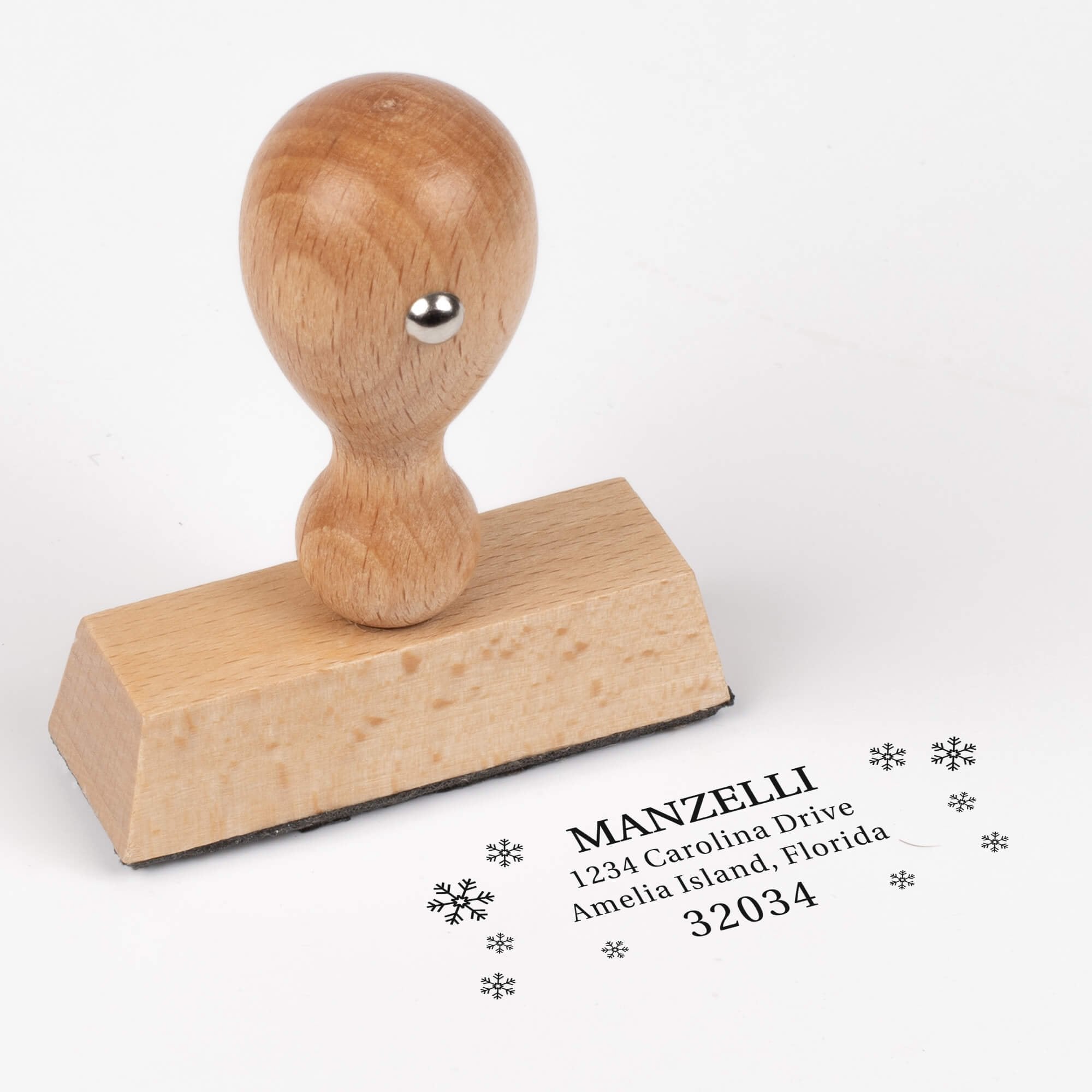 European wood hand stamp shown from above featuring custom ‘Manzelli Snowflake’ holiday return address design.