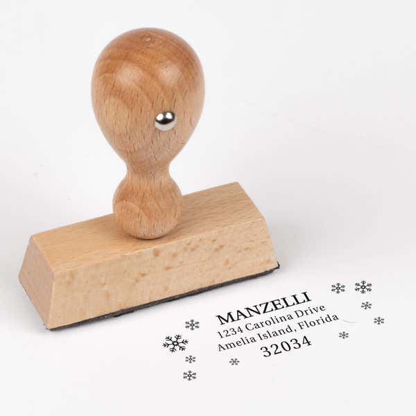 European wood hand stamp shown from above featuring custom ‘Manzelli Snowflake’ holiday return address design.