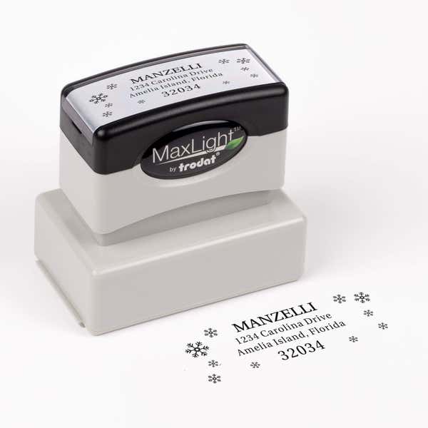 Pre-inked stamp shown from above featuring custom ‘Manzelli Snowflake’  holiday return address design.