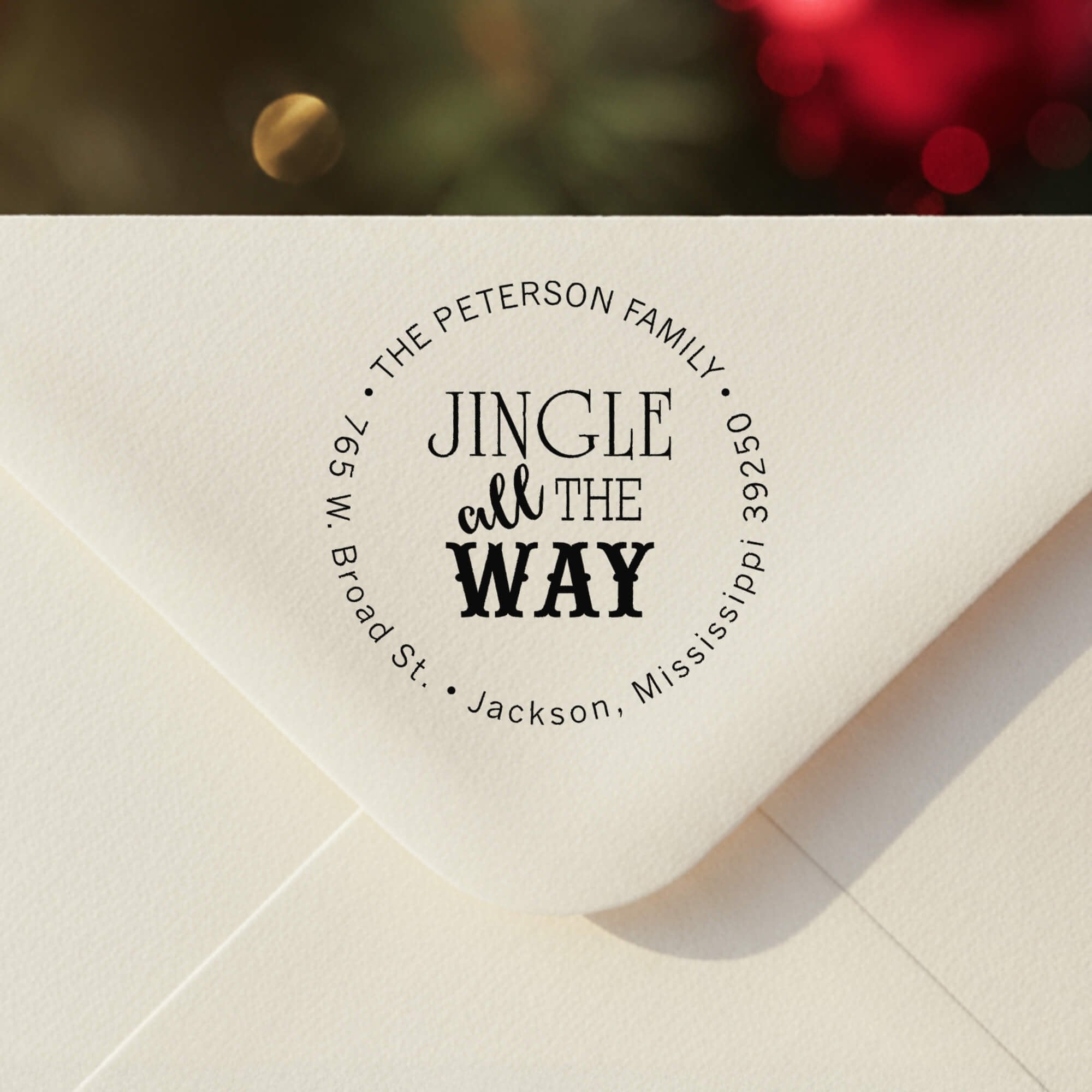Personalized round ‘Jingle All The Way’ address stamp impression on envelope flap for holiday cards.